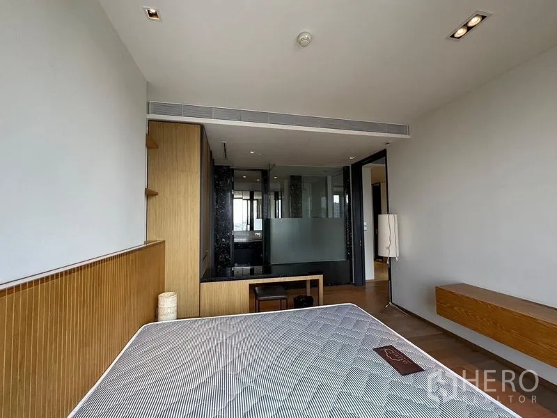 Condominium for rent - Bright bedroom with bed, built-in desk and a glass partition leading to the bathroom.