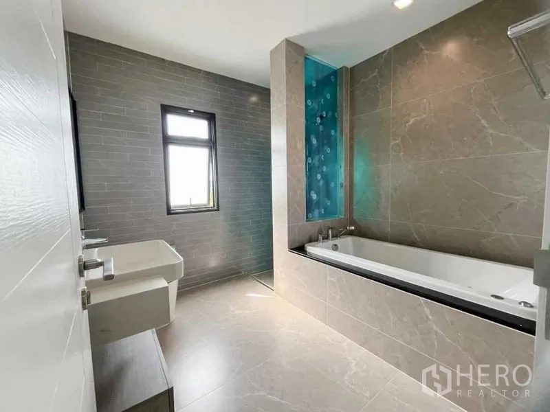 Detached House for sale in Mueang Nonthaburi, Nonthaburi - Contemporary bathroom with built-in soaking tub, twin basins, and a window.
