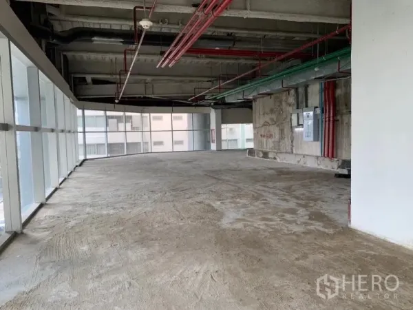 Retail Space for rent - Corner retail space with wraparound glazing, exposed piping and unfinished concrete floor.