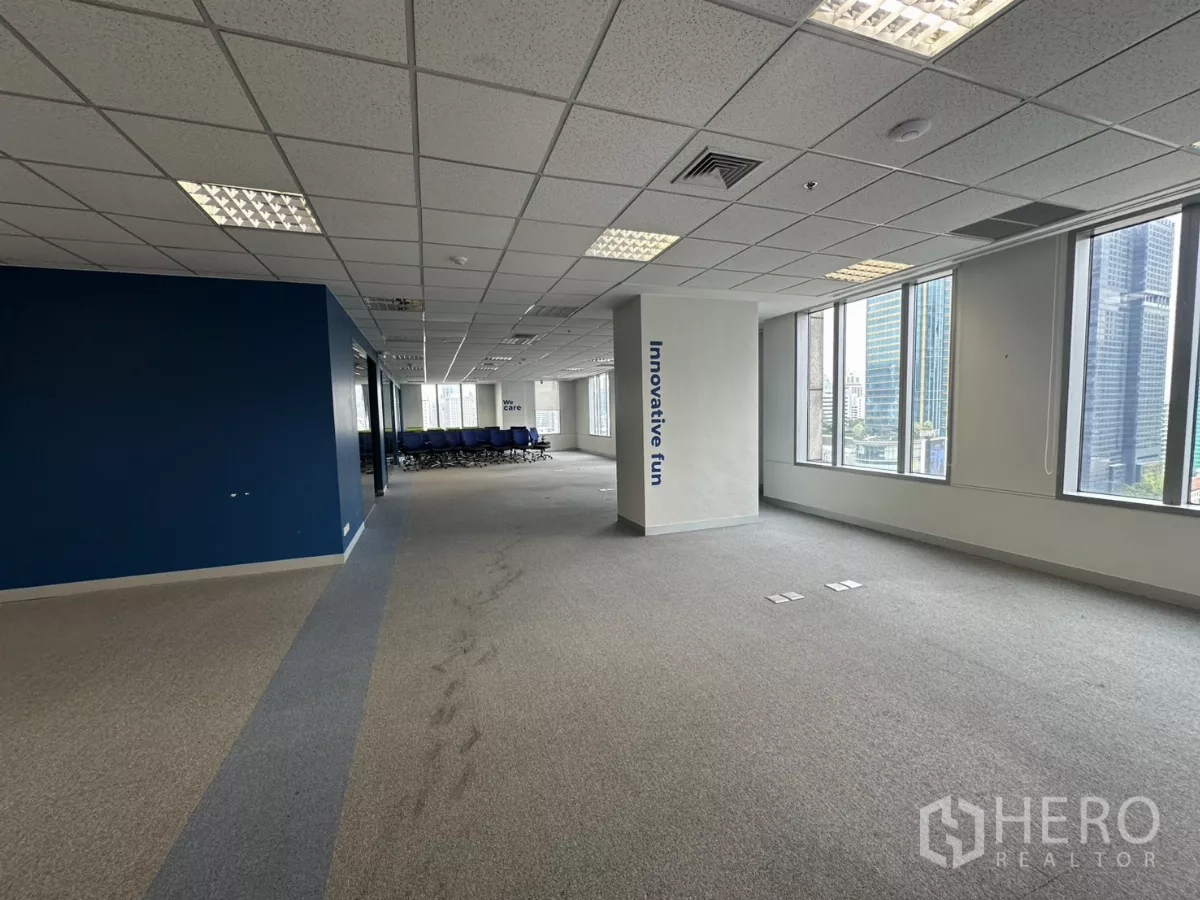 Office Space for rent in Watthana, Bangkok - Open corridor lined with windows and a blue feature wall, city buildings outside.