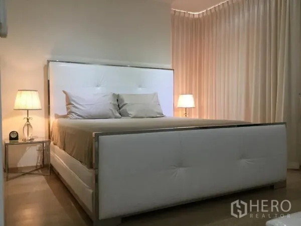 Condominium for rent or sale in Watthana, Bangkok - Cozy master bedroom with an upholstered white bed and bedside lamps.