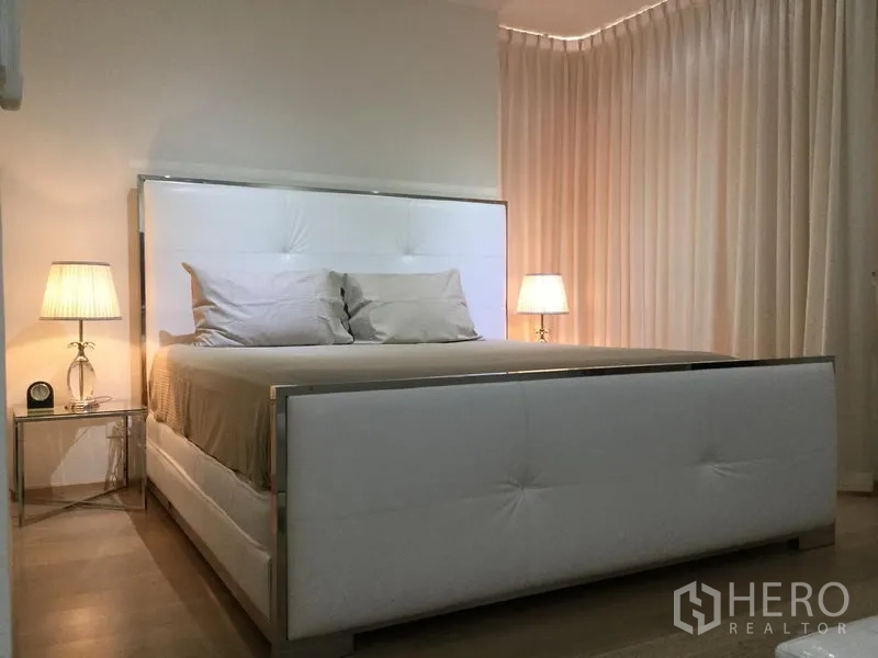 Condominium for rent or sale in Watthana, Bangkok - Cozy master bedroom with an upholstered white bed and bedside lamps.