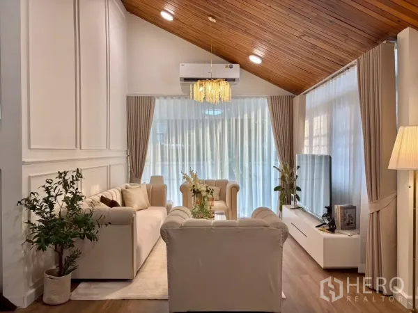 独立式住宅 出租在Huai Khwang, Bangkok - 客厅采光充足，木质斜顶配水晶吊灯与米色沙发