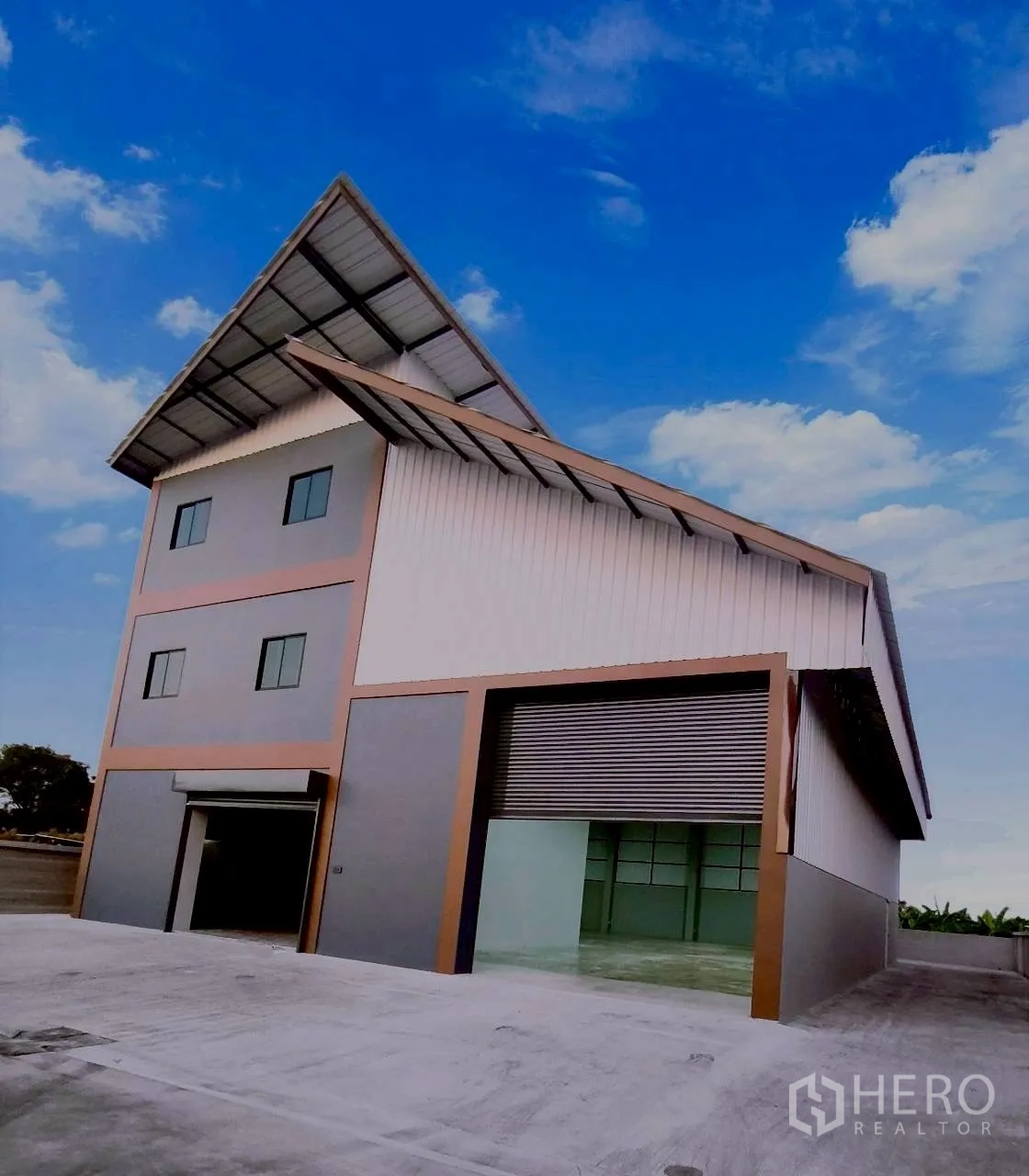Warehouse for rent in Mueang Nonthaburi, Nonthaburi - Warehouse exterior with high gable roof, large roller shutter, and concrete yard.