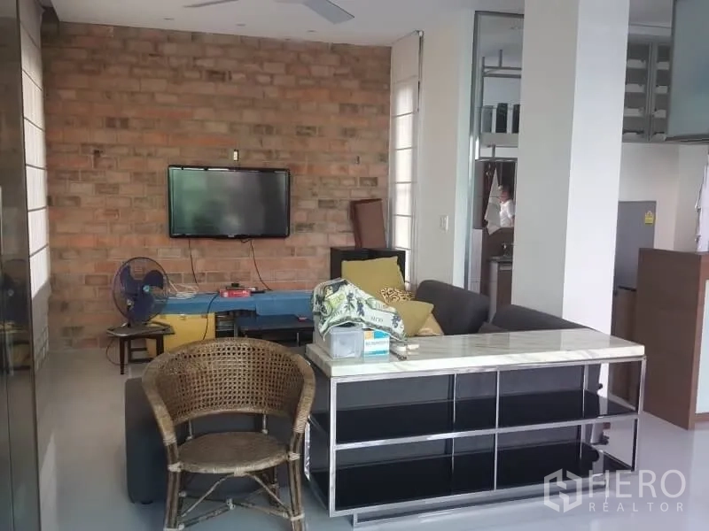 Home Office for rent or sale in Bang Rak, Bangkok - Lounge with exposed brick feature wall, mounted TV and casual seating.