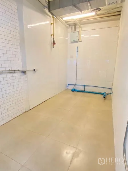 Retail Space for rent in Watthana, Bangkok - Utilities corner of the unit with white tiled walls, plumbing lines, and lighting.