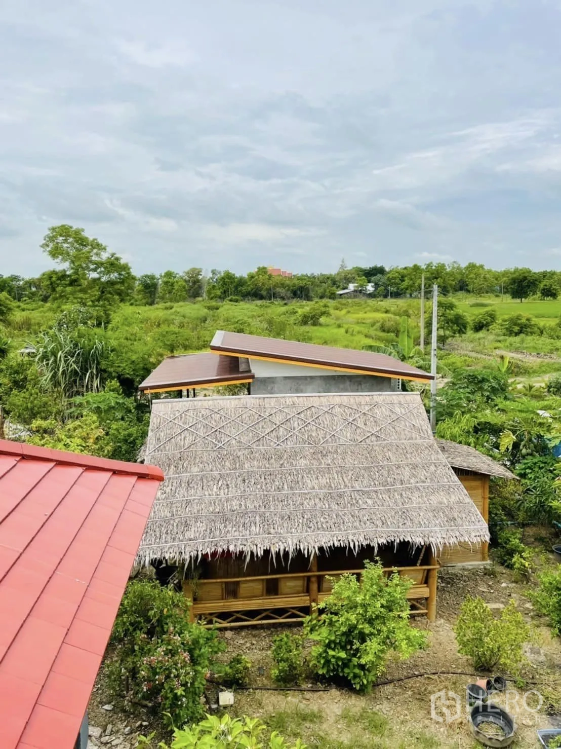 Warehouse for rent or sale in Pathum Thani - Thatched pavilion set among trees and landscaped greenery within the compound.