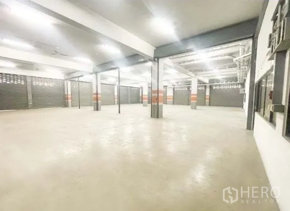 Warehouse for rent in Bang Phli, Samut Prakan - Spacious warehouse interior with concrete floor, columns, multiple roller shutter bays and bright LED lighting.