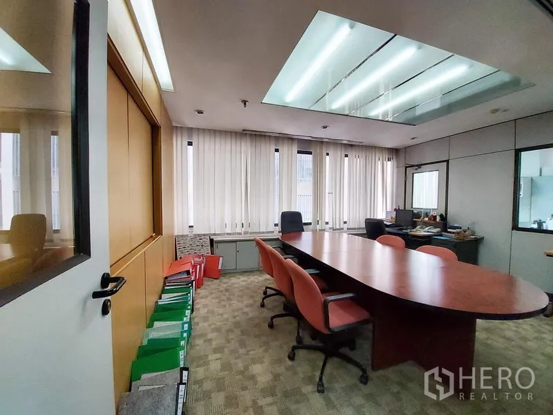 Office Space for rent in Ratchathewi, Bangkok - Boardroom with long oval meeting table, executive chairs, skylight-style ceiling lights and vertical blinds beside glass partitions.