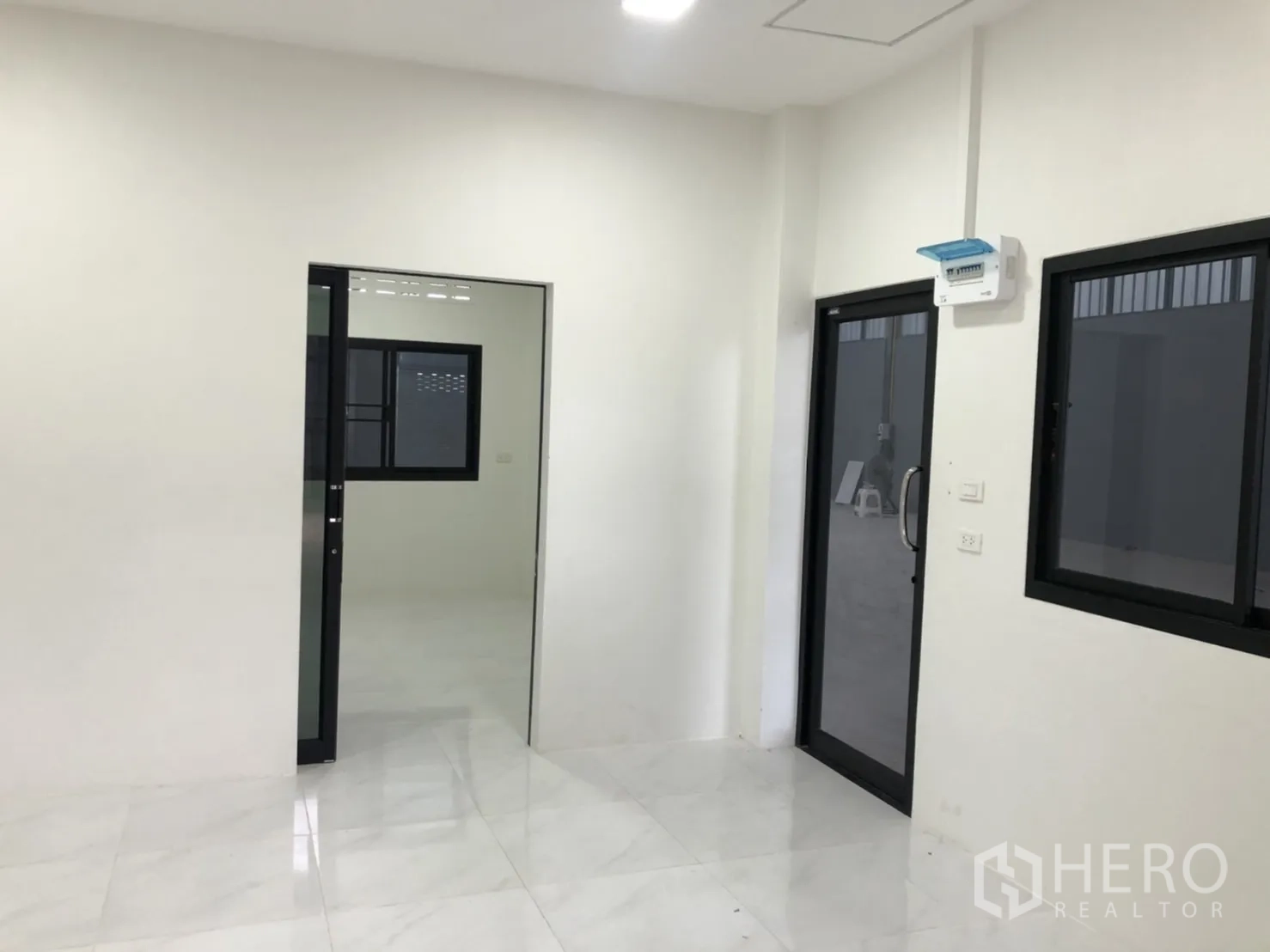 Warehouse for rent in Lam Luk Ka, Pathum Thani - Bright administrative office with white walls, black-framed windows and a glass door to the warehouse floor.