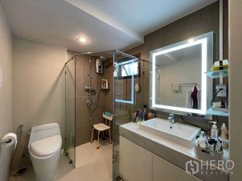 Home Office for rent in Watthana, Bangkok - Modern bathroom with glass shower enclosure, illuminated mirror and vanity.