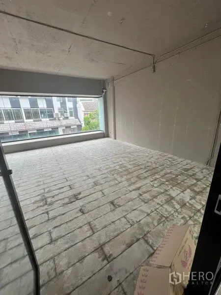 Retail Space for rent in Watthana, Bangkok - Rectangular back area with large picture window and raw concrete ceiling.