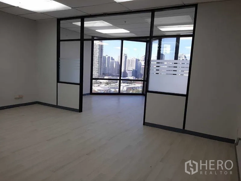 Office Space for rent in Khlong Toei, Bangkok - Open workspace leading to a glass-walled corner room with city views.