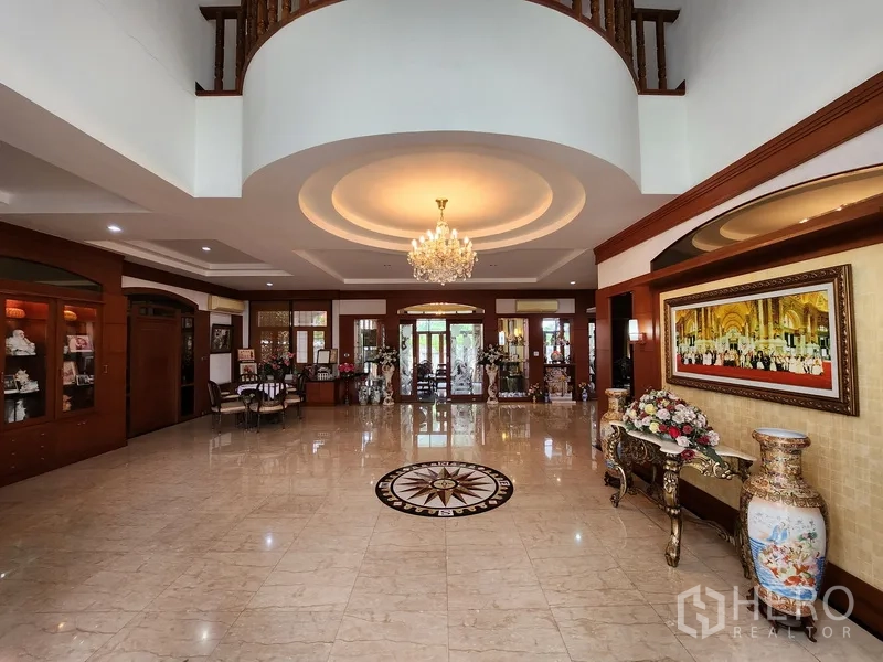 Detached House for rent in Prawet, Bangkok - Double‑height living hall featuring chandelier, marble flooring and compass inlay at the center.