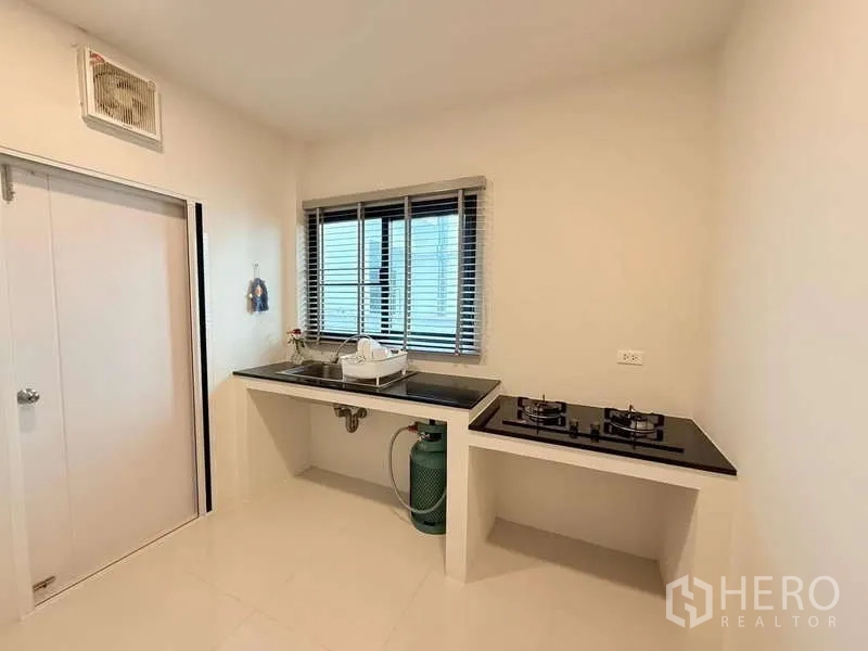 Detached House for sale in Bang Phli, Samut Prakan - Kitchen corner featuring double gas hob and stainless sink on dark countertops.