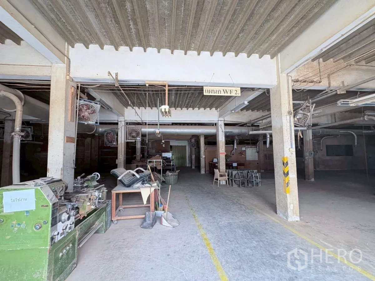 Factory for rent or sale in Bang Khun Thian, Bangkok - Large workshop bay with concrete columns, extraction ducts and workstations.