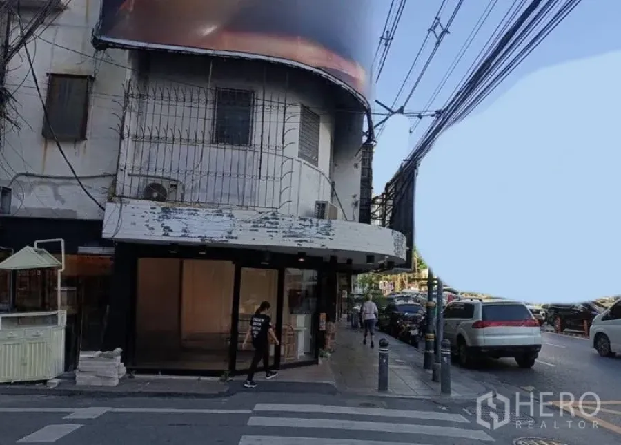 零售空间 出租在Watthana, Bangkok - 街景中的转角商铺，宽阔展示窗正对繁忙道路