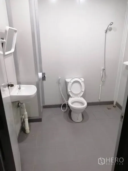 Warehouse for rent or sale in Lam Luk Ka, Pathum Thani - Clean restroom with toilet, sink, handheld bidet, and shower inside the warehouse.