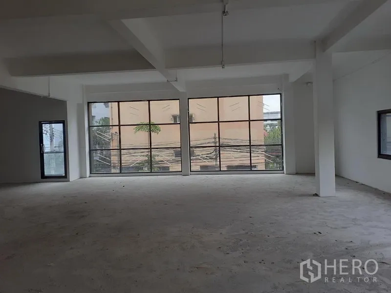 Office Space for rent in Khlong Toei, Bangkok - Bright shell office interior featuring floor-to-ceiling black-framed windows and a side glass entry door.
