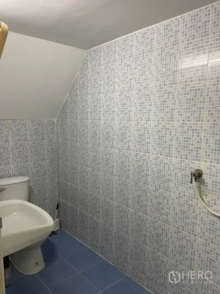 Shophouse for rent in Khlong Toei, Bangkok - Bathroom with mosaic wall tiles, toilet, and sink on a blue tiled floor.