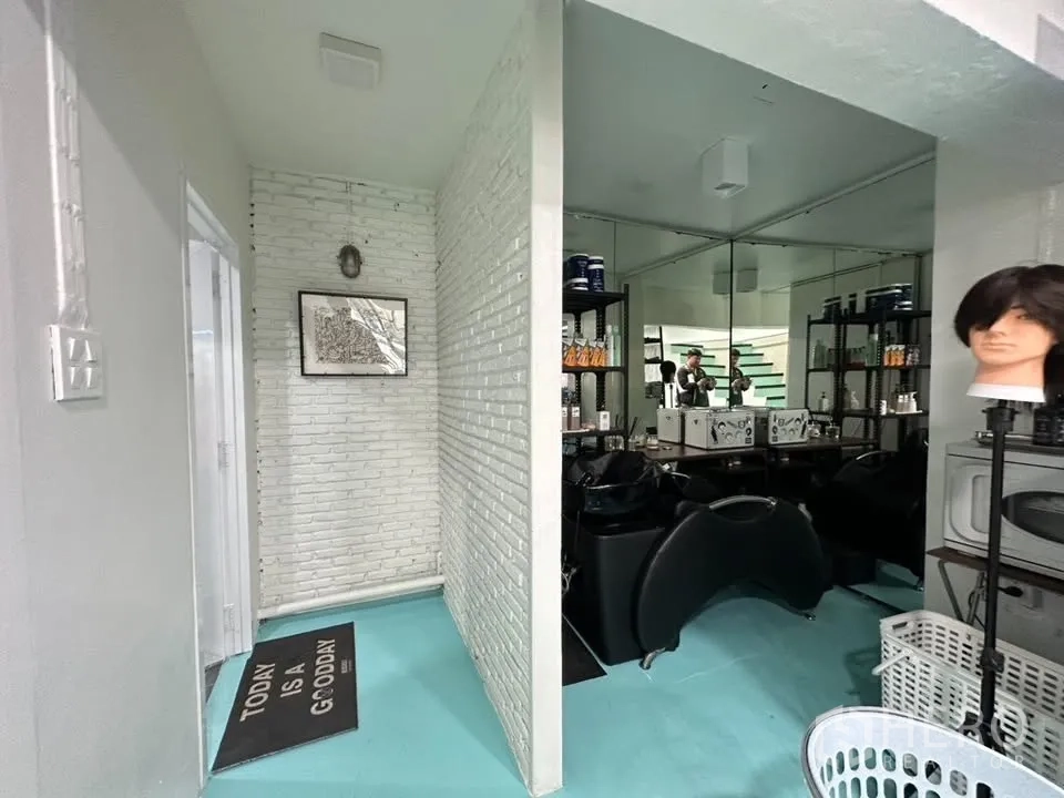 Shophouse for sale in Watthana, Bangkok - Shampoo room with mirrors, shelving, and white brick feature walls beside a corridor.