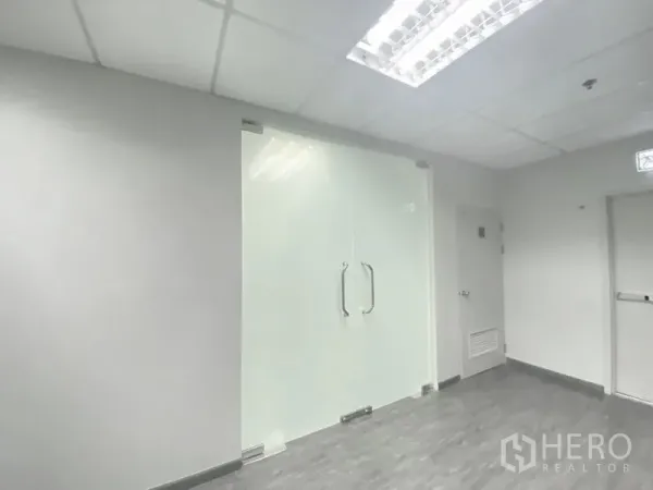Office Space for rent in Chatuchak, Bangkok - Frosted glass double doors with metal handles in a modern office entry, under grid ceiling lighting.