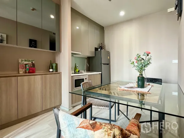Condominium for rent in Pathum Wan, Bangkok - Open-plan kitchenette with ample storage and a glass dining table for two.