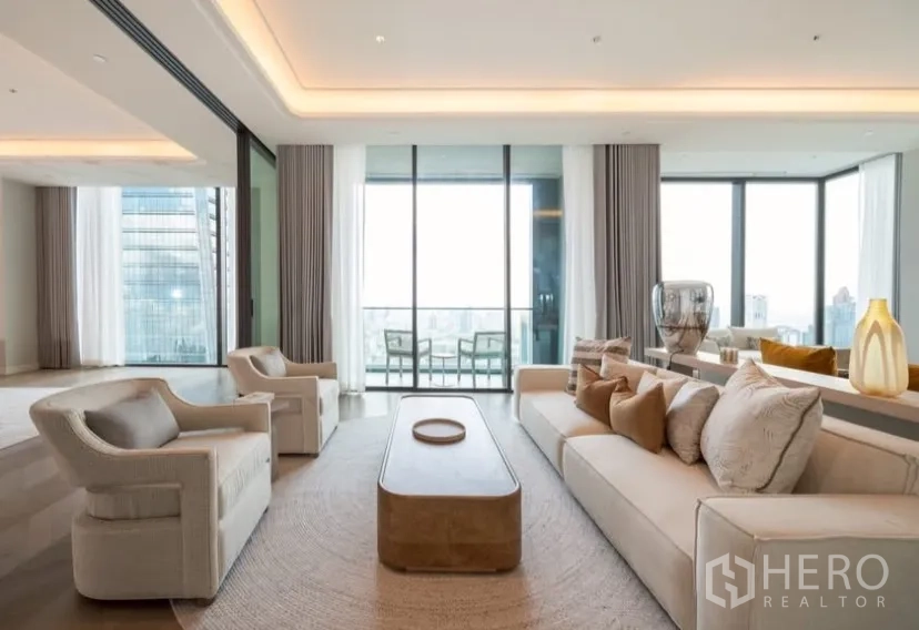 Condominium for rent or sale in Pathum Wan, Bangkok - Expansive living area with plush sofas and sliding doors to a balcony overlooking Bangkok.