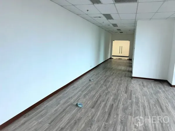 Office Space for rent in Watthana, Bangkok - Long open-plan office area with white walls, vinyl wood floors, and double glass entry doors.