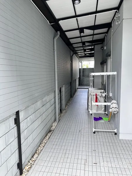 Detached House for sale in Prawet, Bangkok - Covered utility corridor with tiled floor and laundry area.