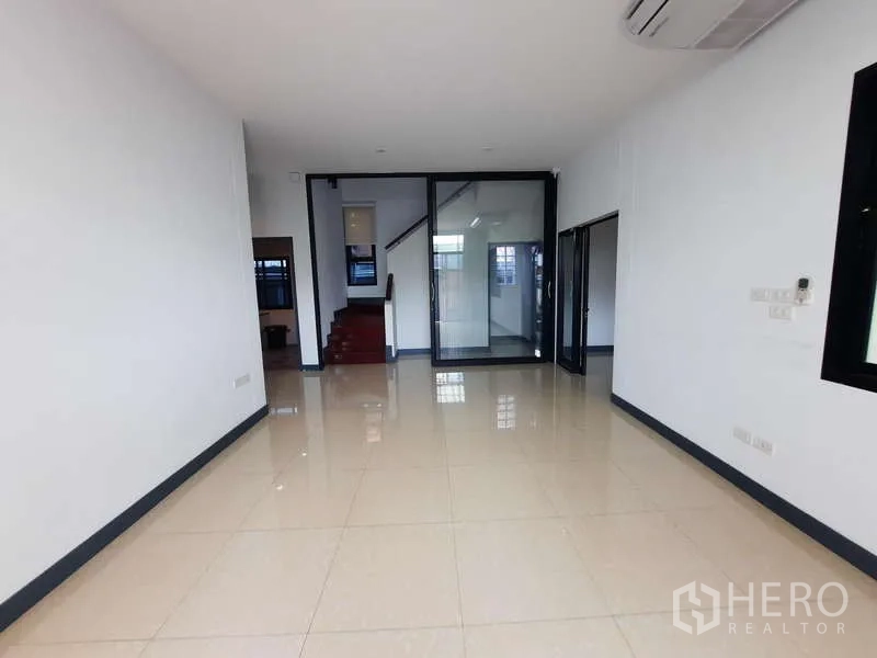 Home Office for rent in Huai Khwang, Bangkok - Open-plan room with glossy tiled floor and a glass partition beside the staircase.