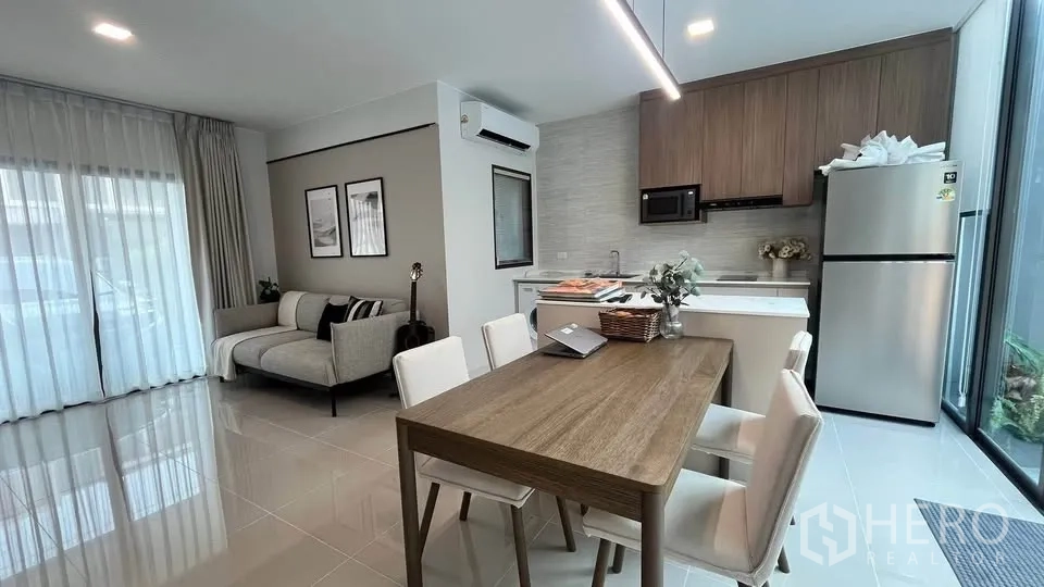 Townhouse for rent or sale in Bang Phli, Samut Prakan - Dining table beside kitchen and tall glass wall opening to patio.