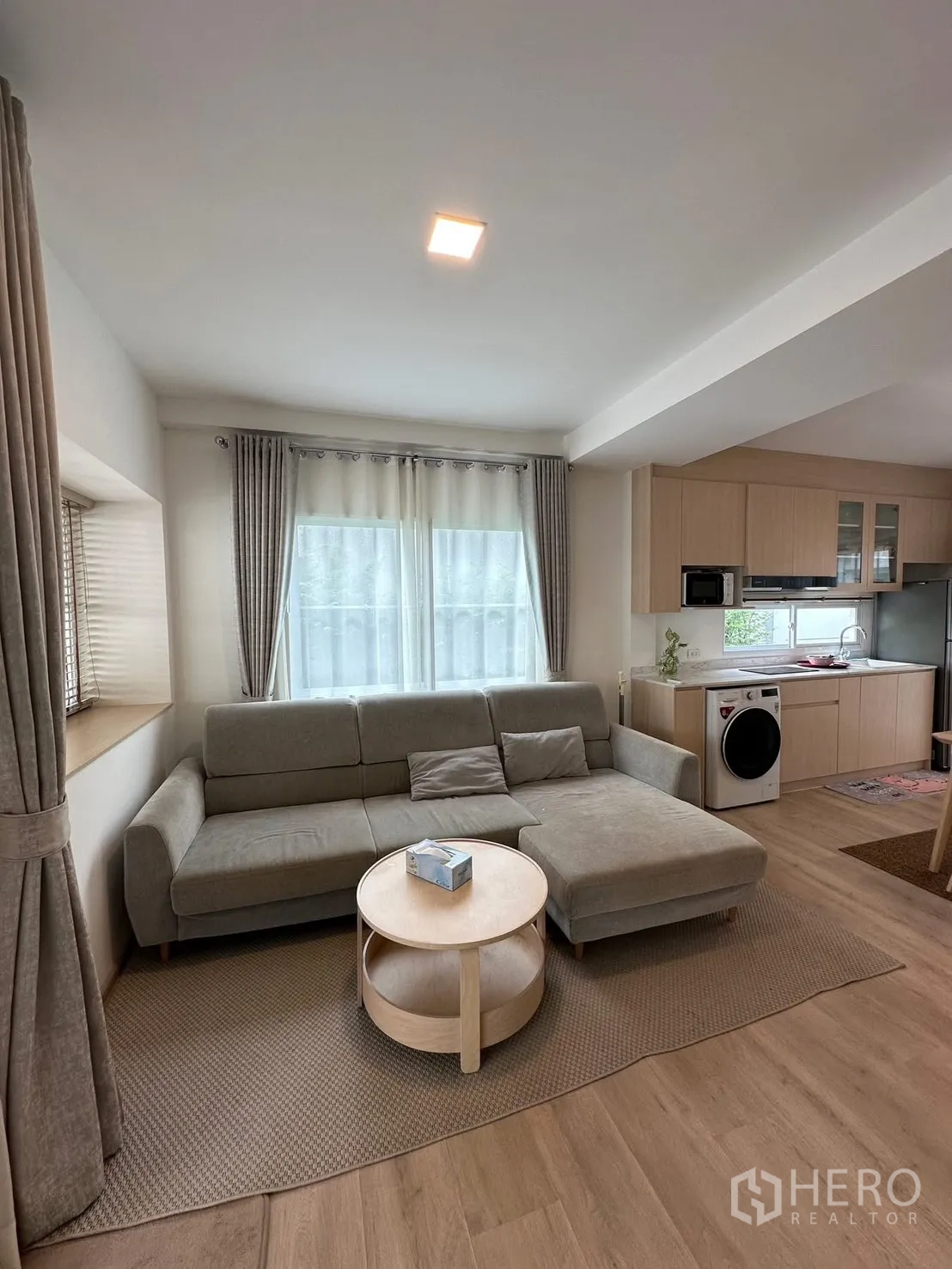联排别墅 for rent in Prawet, Bangkok - 开放式起居区，L型沙发与一体化厨房相连。