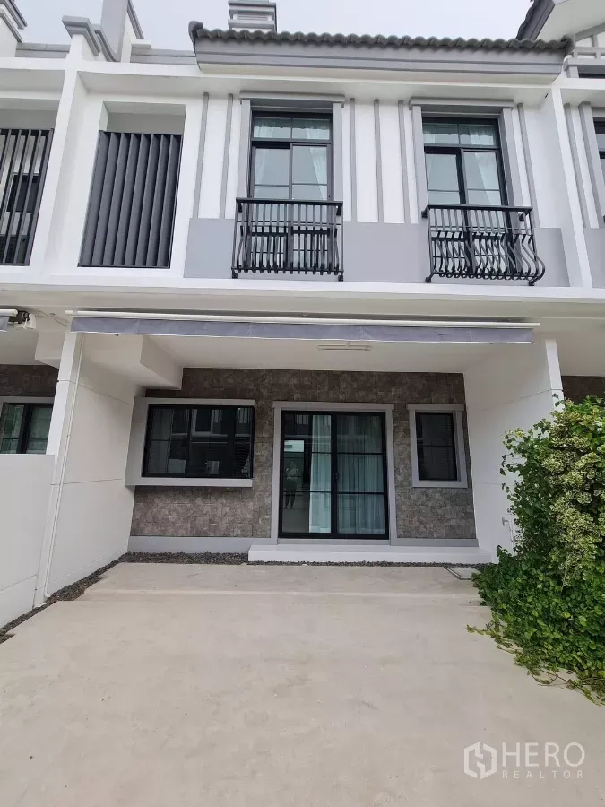 Townhouse for rent in Bang Phli, Samut Prakan - Modern two-storey townhouse facade with covered two-car parking and balcony railings