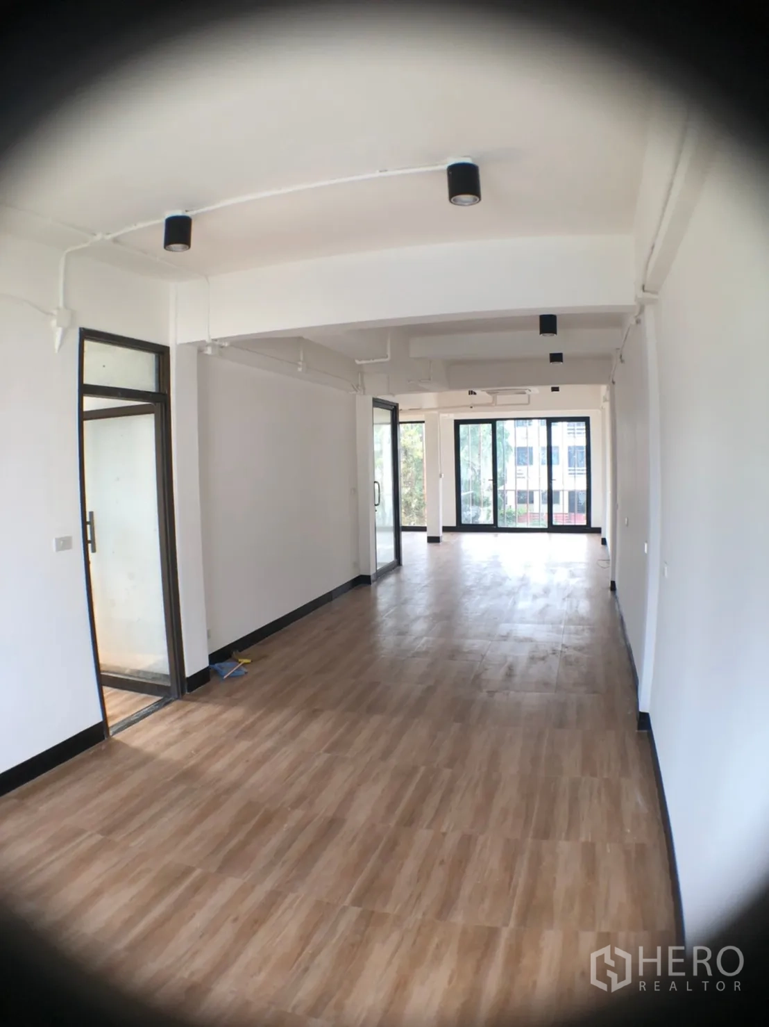 Home Office for rent in Phra Khanong, Bangkok - Long open-plan office floor with wood-look tiles, white walls and sliding glass doors.