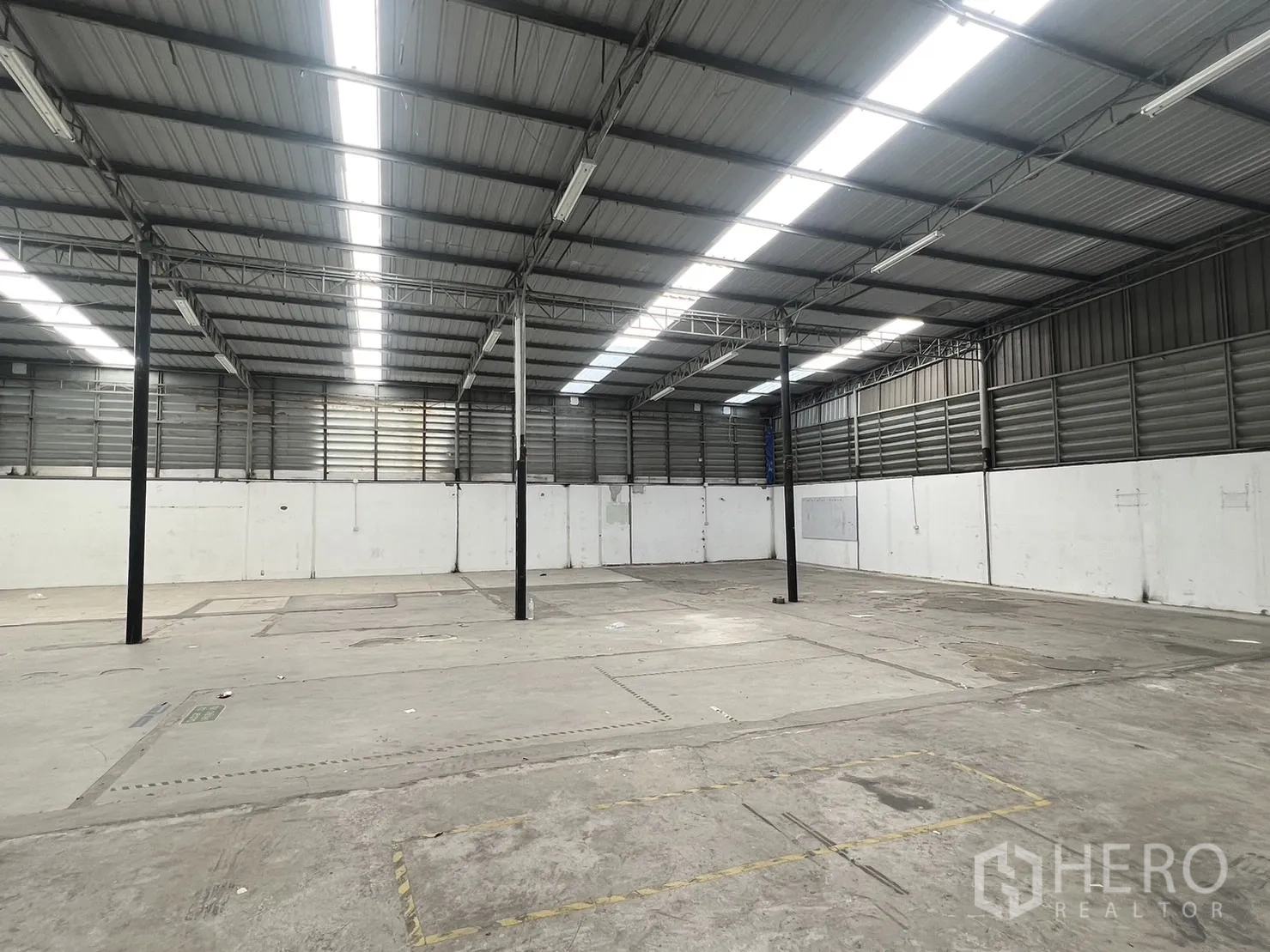 Warehouse for rent in Suan Luang, Bangkok - Open-plan storage space with concrete floor, steel columns, and bright strip lighting.