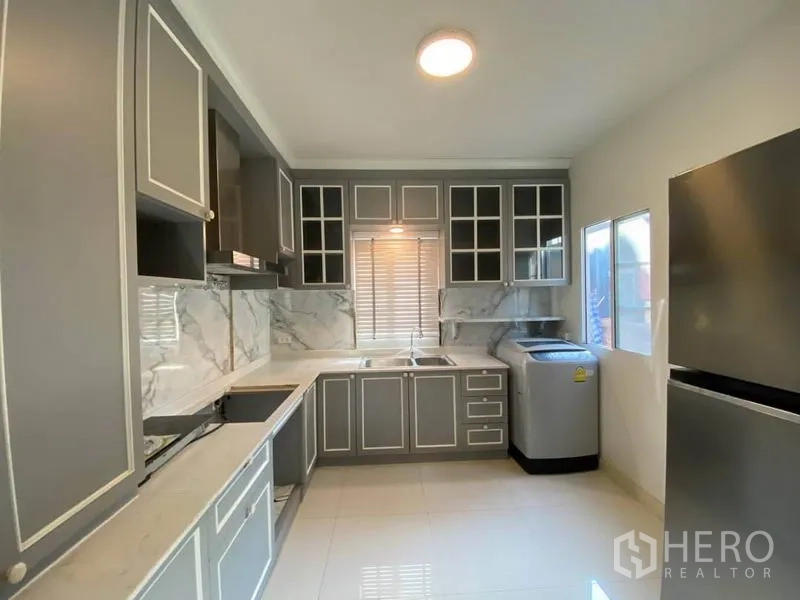 Detached House for rent in Suan Luang, Bangkok - Fully fitted kitchen with grey cabinets, marble backsplash, windows, refrigerator and washing machine.
