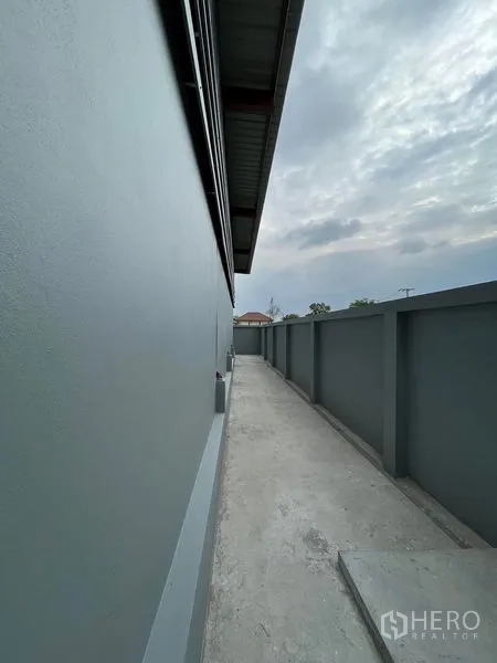 Warehouse for rent in Khlong Sam Wa, Bangkok - Long side corridor beside the warehouse with solid boundary wall and roof overhang for protected access.