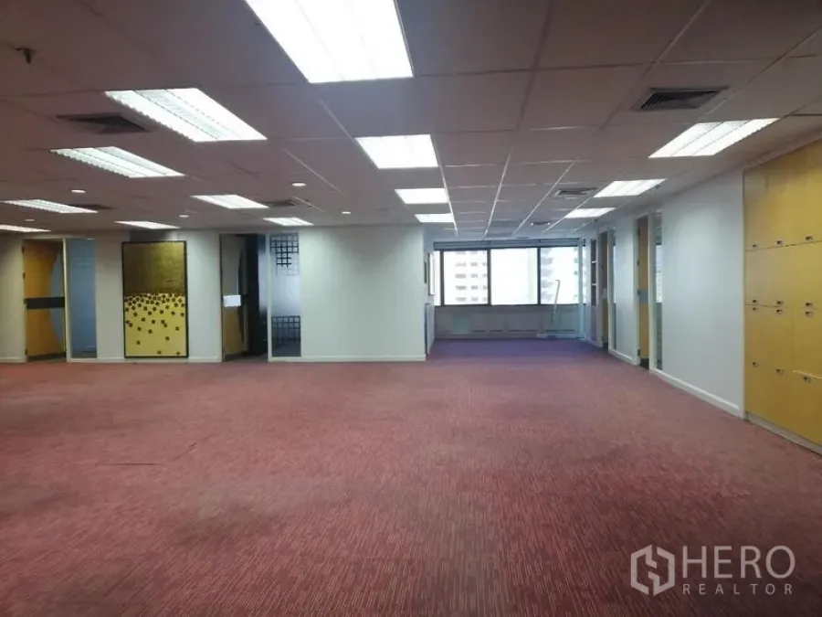 Office Space for rent in Watthana, Bangkok - Open workspace with red carpet, partitioned rooms and ceiling lights facing wide city windows.