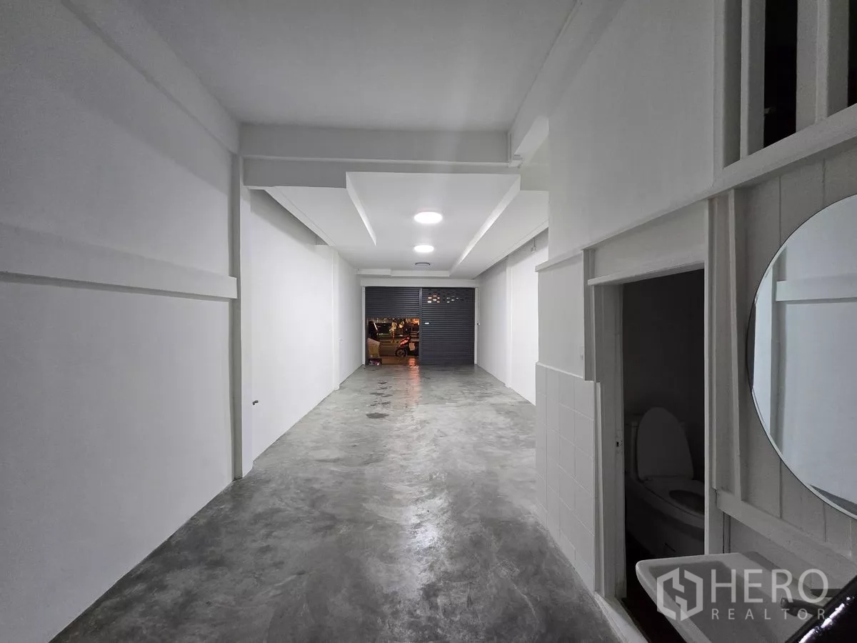 Shophouse for rent in Watthana, Bangkok - Ground‑floor shop bay with rolling shutter to the street and restroom access.