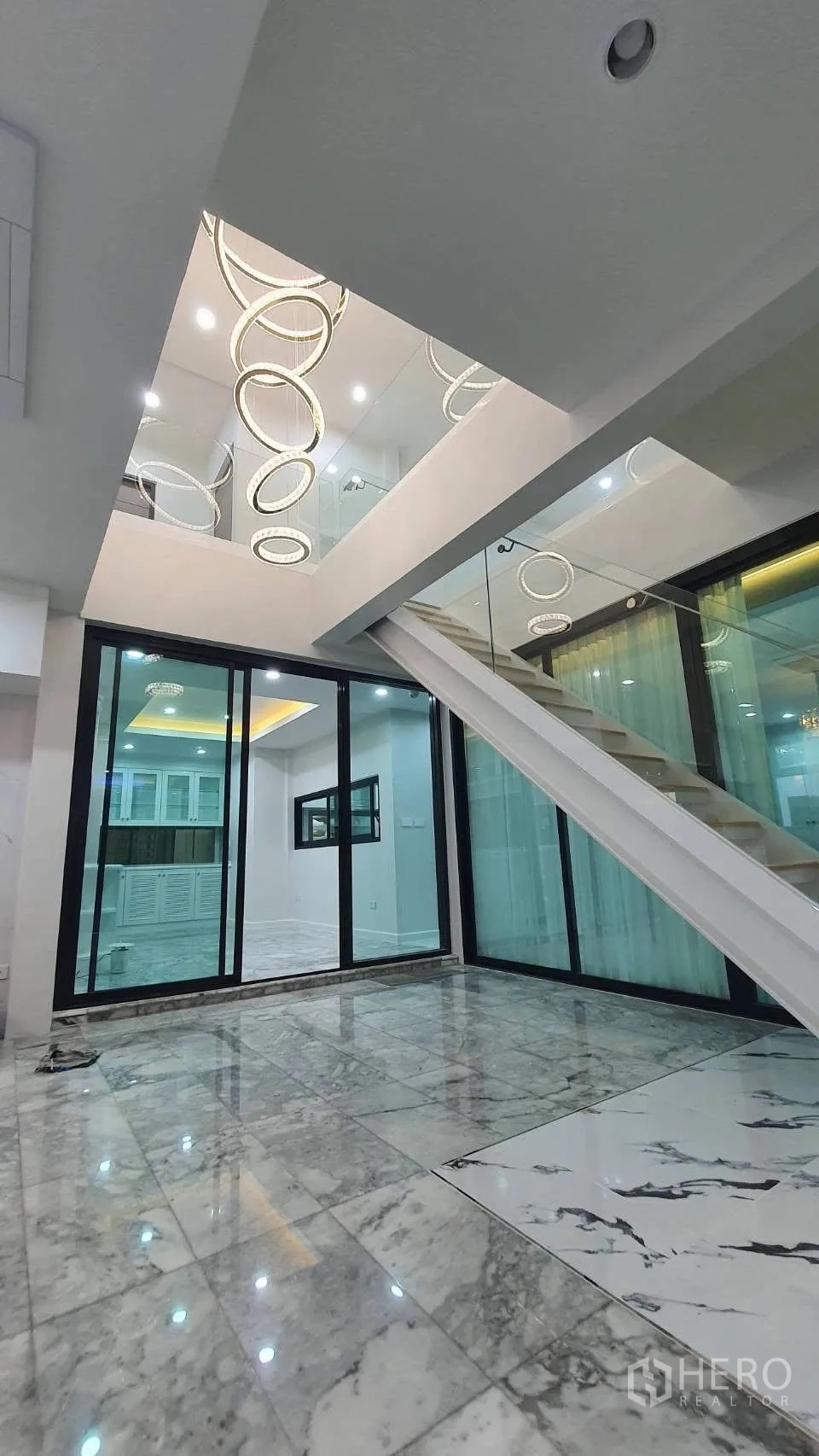 独栋房屋 for rent in Lat Phrao, Bangkok - 玻璃墙楼梯旁的推拉门与大理石地面。