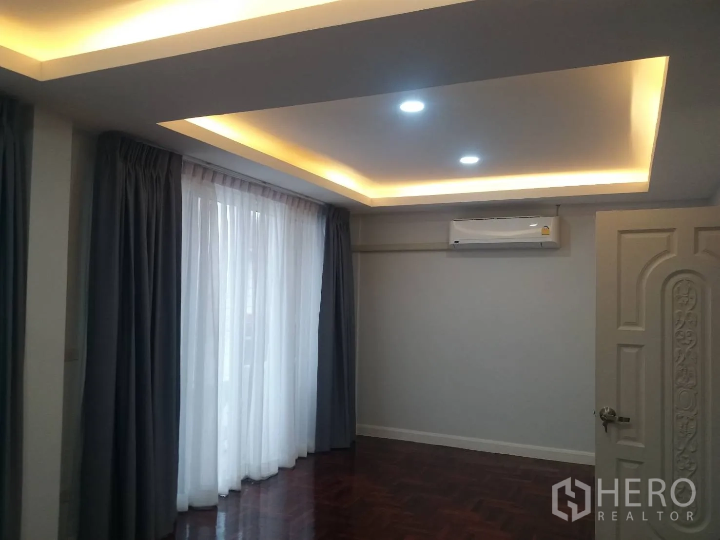 Townhouse for rent in Khlong Toei, Bangkok - Bedroom with cove ceiling lighting, full-length curtains and a wall-mounted air conditioner.