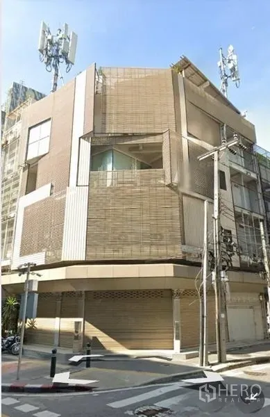 Retail Space for rent - Corner multi‑storey retail building with roller shutters and a modern facade on a Bangkok street.