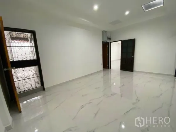 Detached House for rent in Huai Khwang, Bangkok - Spacious living room with glossy marble-look floors and dark wood doors.