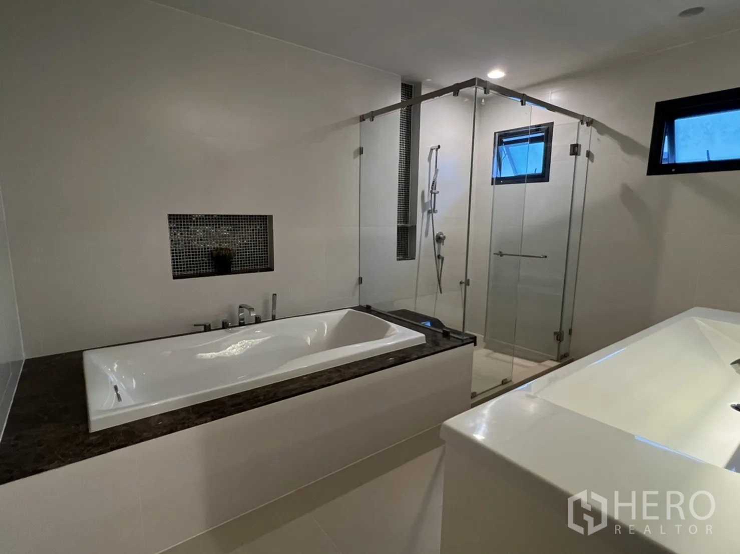 Detached House for rent or sale in Bang Kapi, Bangkok - Modern bathroom with a bathtub, double vanity and glass-enclosed shower.