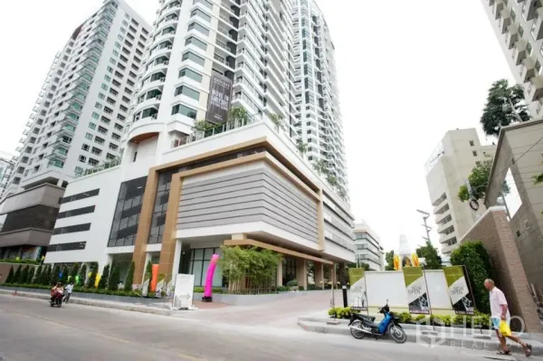 Condominium for rent or sale in Khlong Toei, Bangkok - Modern high-rise condominium exterior with landscaped entrance and driveway in Khlong Toei.