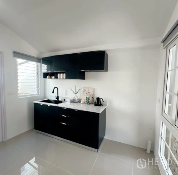 Detached House for rent in Mueang Samut Prakan, Samut Prakan - Fitted kitchen with black cabinetry, white countertop, sink and window.