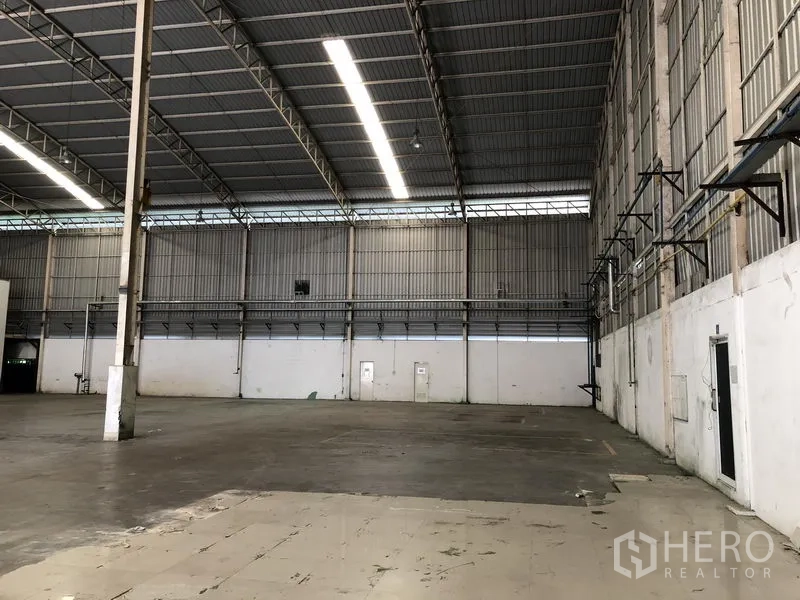 Factory for rent in Phra Nakhon Si Ayutthaya - Section of factory floor with high walls, utility conduits, mezzanine walkway, and support columns.