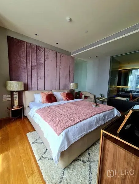 Condominium for rent in Khlong Toei, Bangkok - Master bedroom with pink upholstered headboard and glass wall panel.