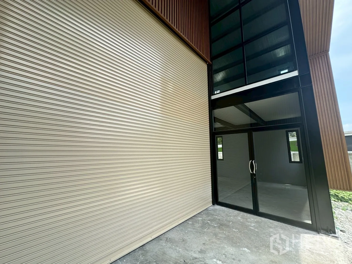 Warehouse for rent in Suan Luang, Bangkok - Close-up of the wide roller shutter and glass office entrance at the warehouse front.